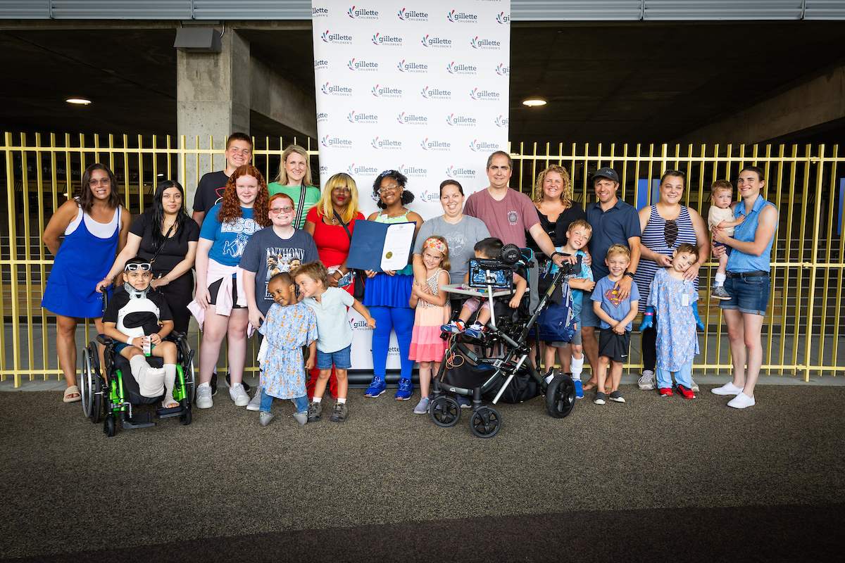 Families hold the Governer's proclaimation in front of a Gillette Children's banner.