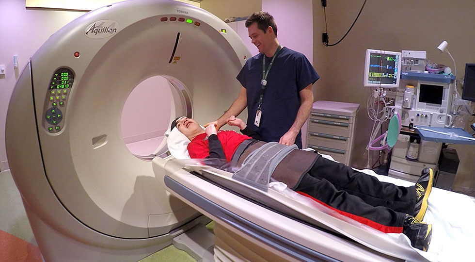 Gillette Children's patient gets CT scan as caregiver looks on.