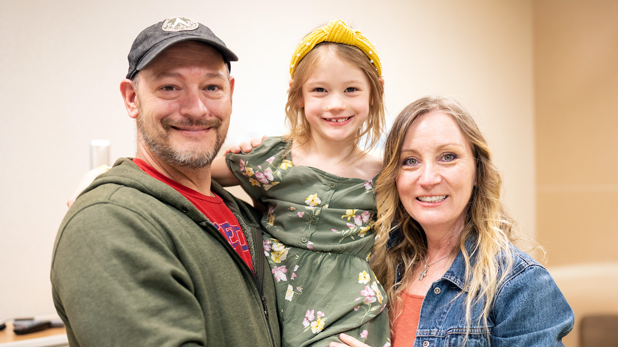 Gillette patient Emma Durward smiles while being held by two family members.