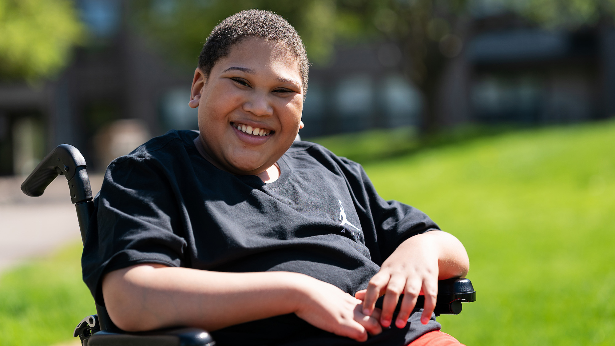 Gillette patient Michael Holley sits in a wheelchair smiling.