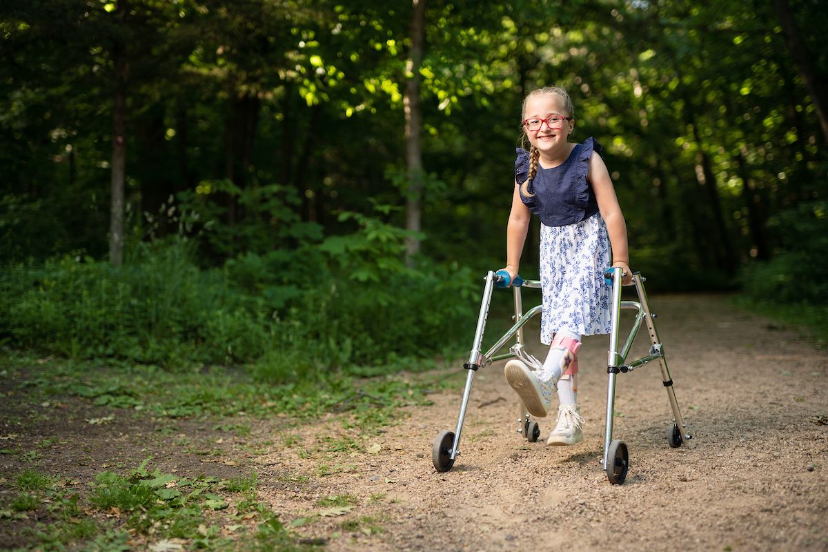 A smiling girl living with cerebral palsy has fun in nature.