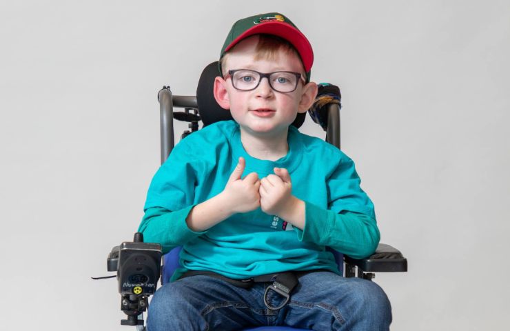 Gillette patient Leo sits in his power chair looking directly at the camera.